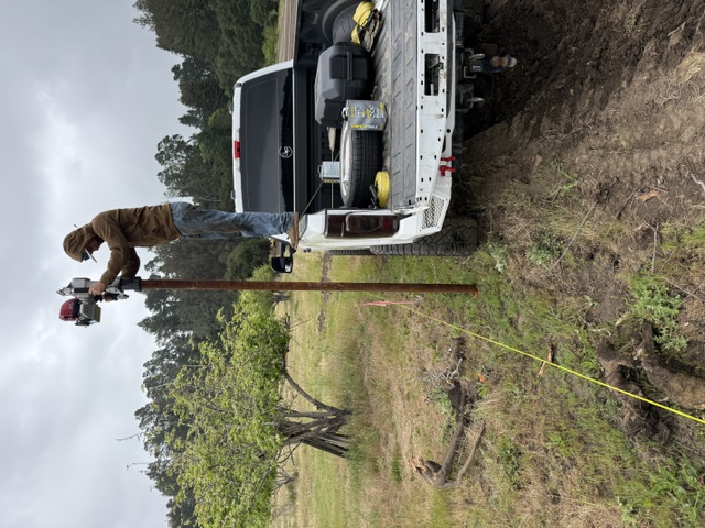Setting a fence post from the truck bed during a livestock fencing job