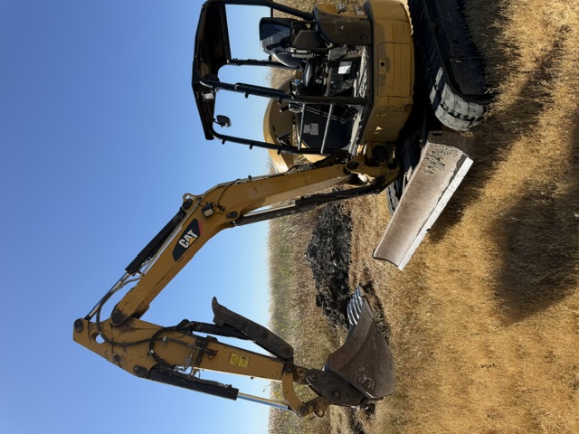 Mini excavator clearing ground on a Central Valley ranch property